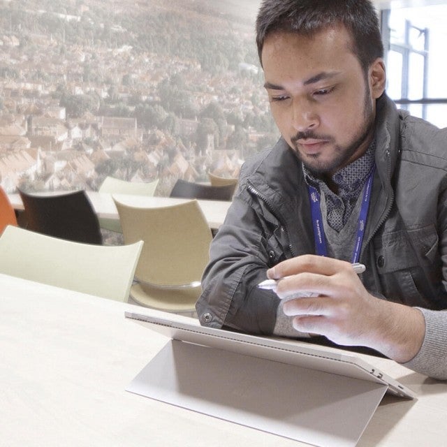 Person sitting at a table drawing on tablet
